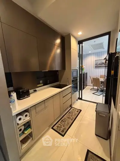 Modern kitchen with sleek cabinetry and open layout leading to dining area.