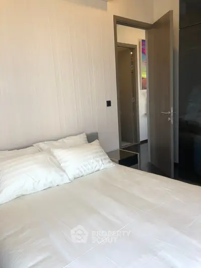 Cozy bedroom with modern decor and open door leading to hallway, perfect for relaxation.