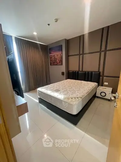 Modern bedroom with stylish decor and natural light, featuring a comfortable bed and sleek furnishings.