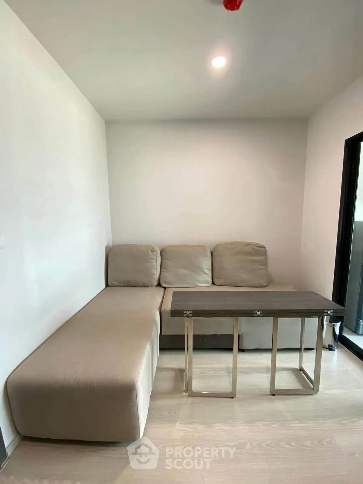 Cozy living room with modern beige sofa and sleek wooden table, perfect for relaxation and entertaining.
