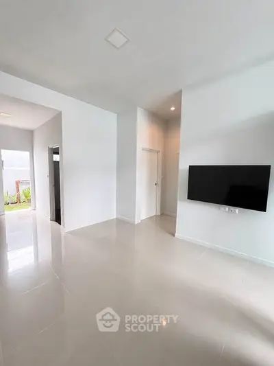 Spacious modern living room with sleek tiled flooring and wall-mounted TV