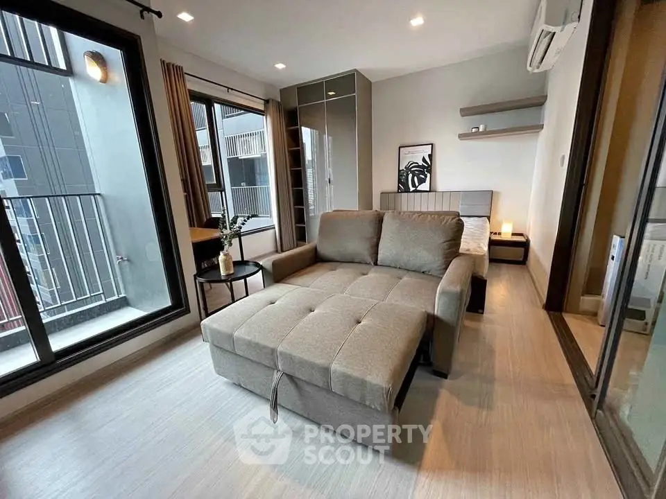 Modern bedroom with stylish decor and large windows offering natural light and city views.