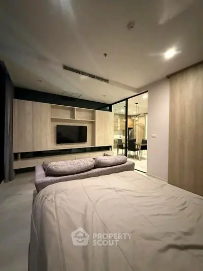 Modern bedroom with stylish built-in entertainment unit and cozy bed in a contemporary apartment.