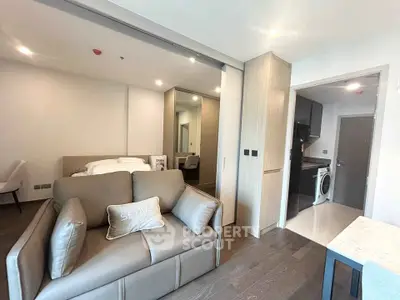 Modern studio apartment with sleek design, featuring a cozy living area and compact kitchen with washing machine.