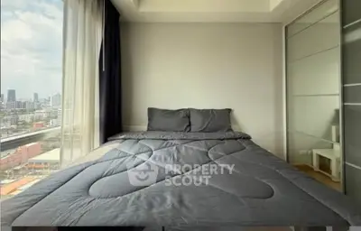Modern bedroom with large window offering stunning city view and sleek design.