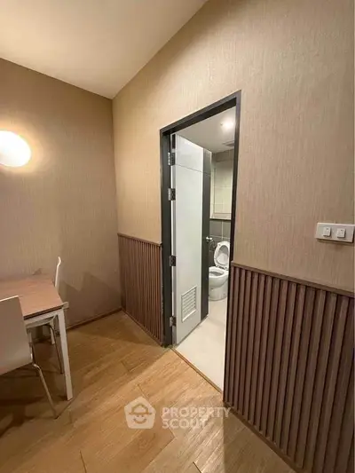 Cozy interior with wooden flooring and modern bathroom access, perfect for compact living spaces.