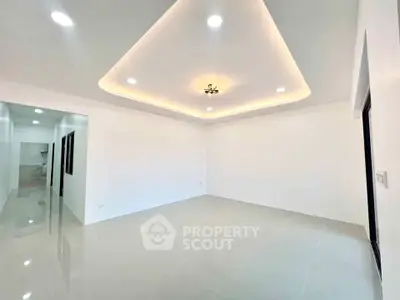 Spacious modern living room with elegant ceiling lighting and glossy tiled floors.
