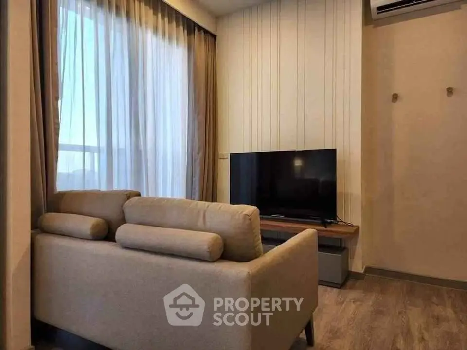 Modern living room with cozy sofa and flat-screen TV, featuring elegant floor-to-ceiling curtains.