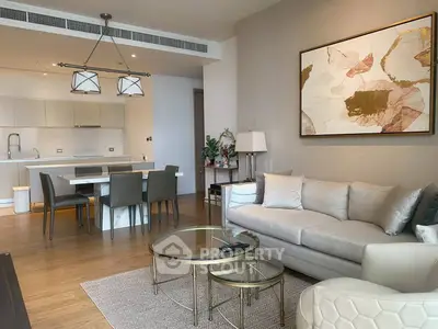 Modern open-plan living room with elegant decor and dining area, featuring stylish furniture and artwork.