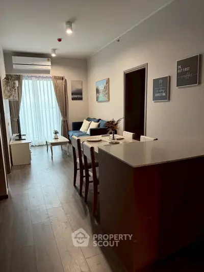 Modern living room with dining area and natural light, featuring stylish decor and cozy ambiance.