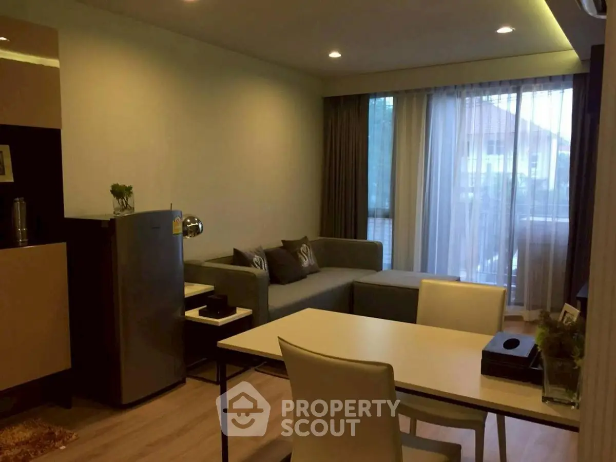 Modern living room with cozy sofa and dining area, featuring large windows and stylish decor.