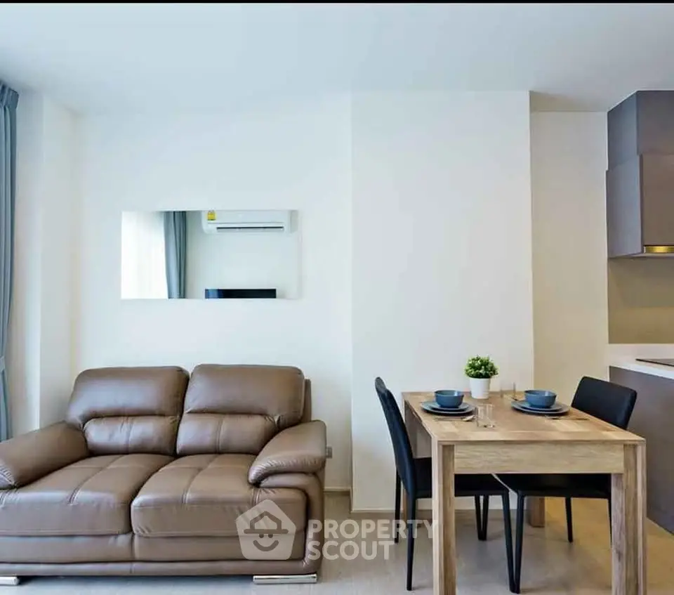 Modern living room with leather sofa and dining area in open layout apartment.