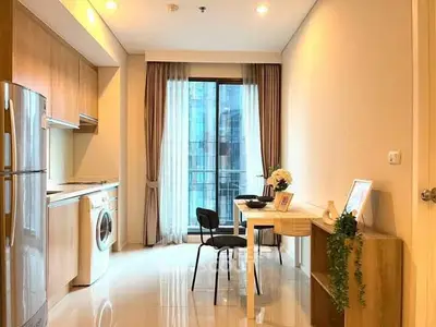 Modern kitchen with dining area, featuring washing machine and sleek appliances.