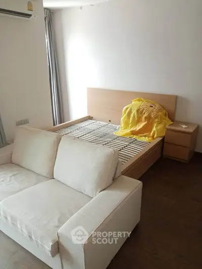 Cozy bedroom with wooden flooring, modern bed, and comfortable sofa, perfect for relaxation.