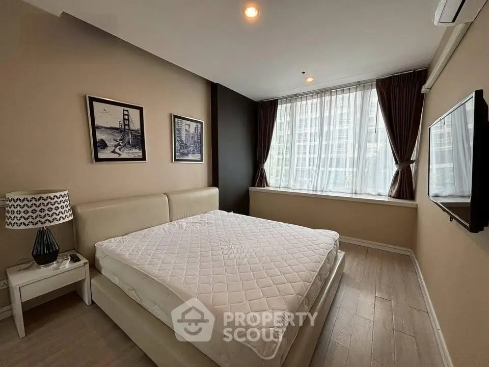 Spacious bedroom with large window and modern decor in urban apartment