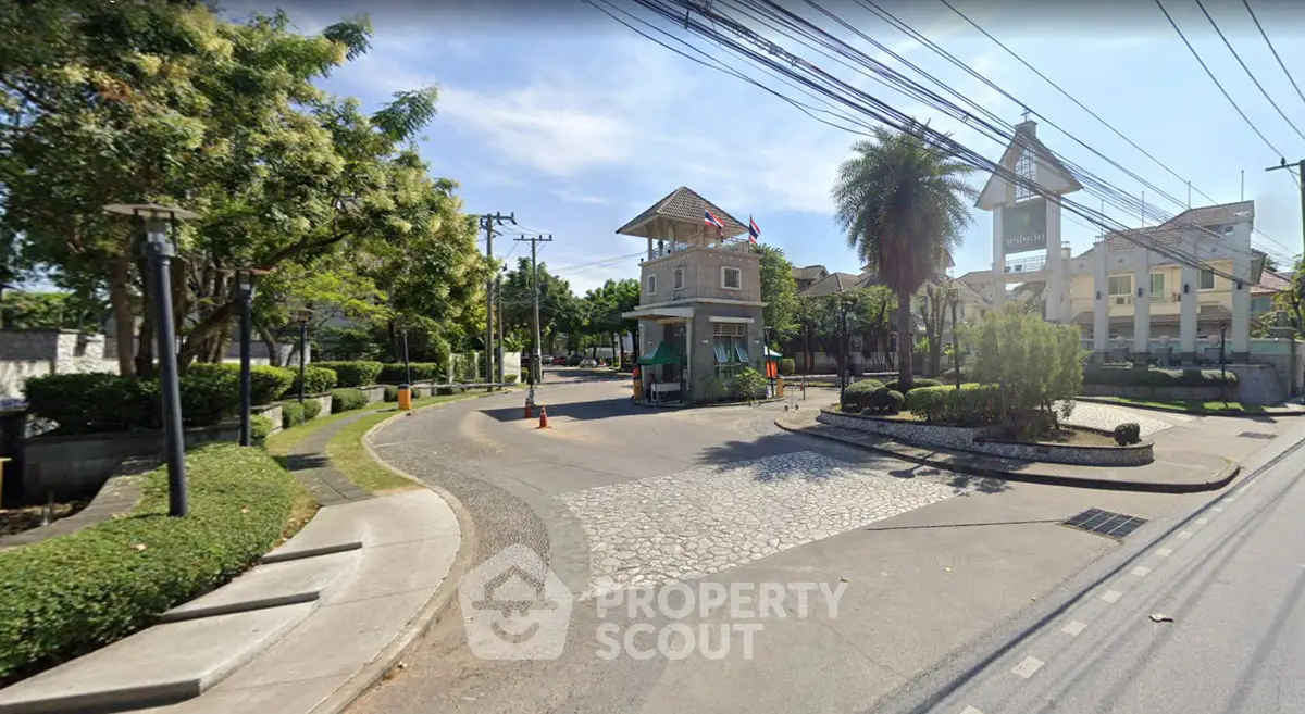 Charming gated community entrance with lush greenery and security post, ideal for serene living.