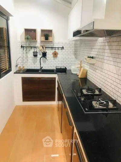 Modern kitchen with sleek black countertops and gas stove in stylish apartment.