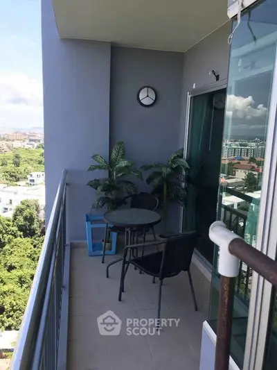 Spacious balcony with seating and lush views in modern high-rise apartment.