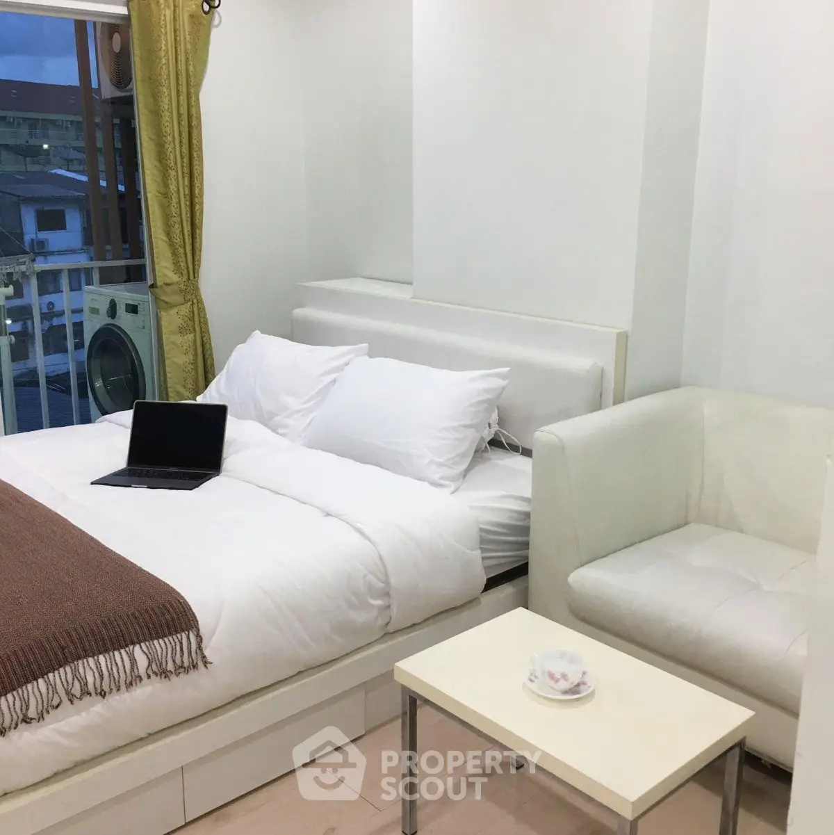 Cozy bedroom with modern decor and city view, featuring a comfortable bed and stylish seating area.
