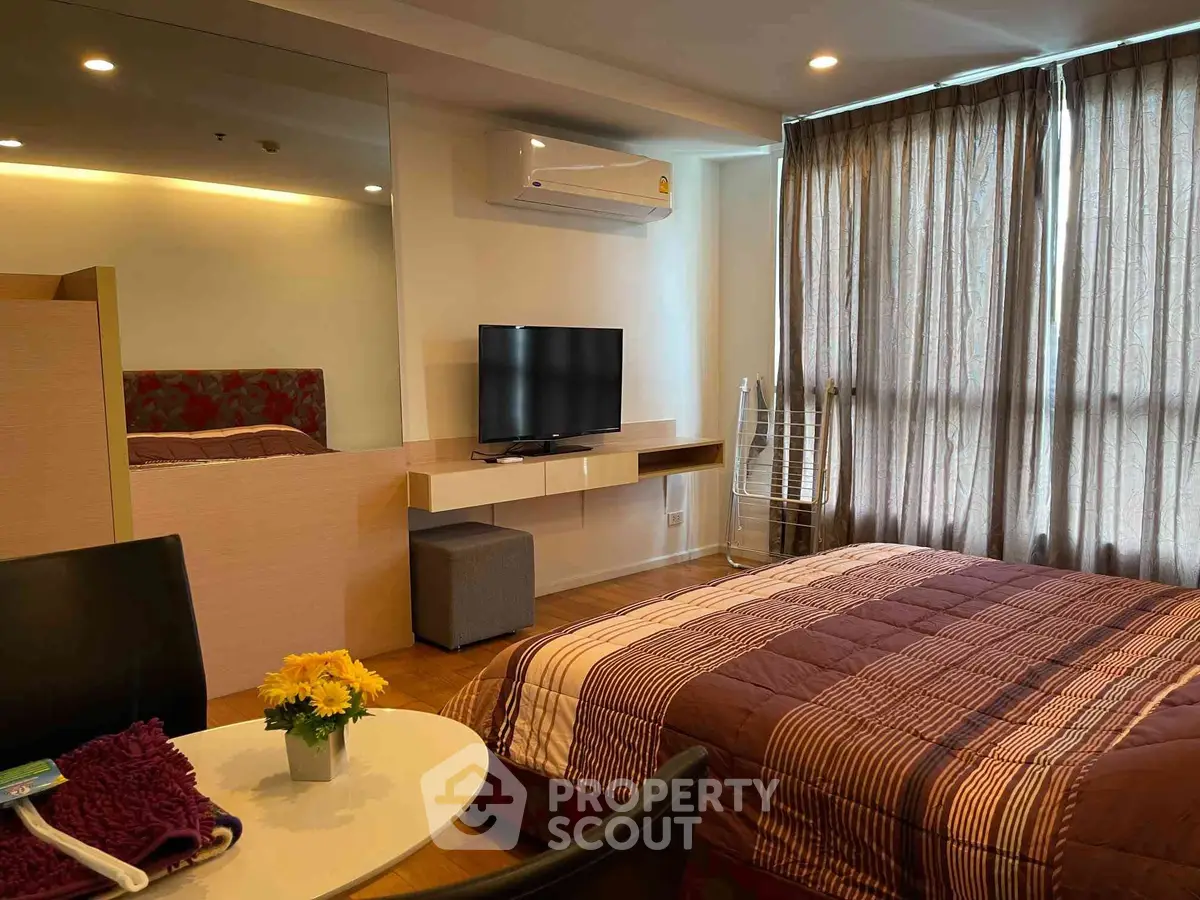 Cozy bedroom with modern decor, featuring a TV, air conditioning, and stylish furniture.
