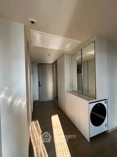 Modern hallway with built-in washer and sleek cabinetry in a contemporary apartment.