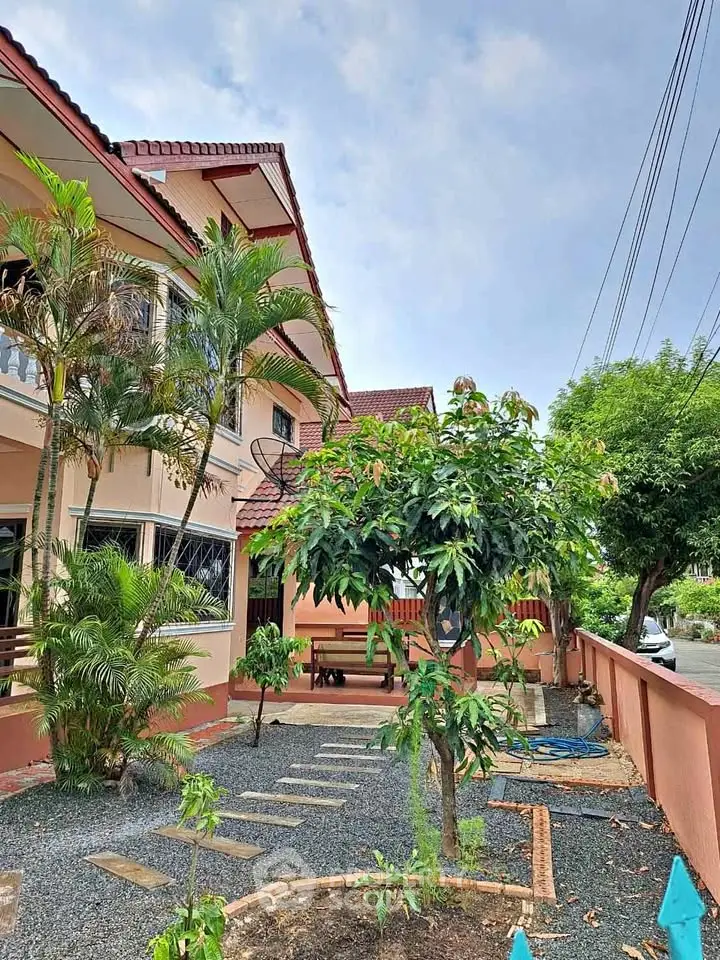 Charming two-story house with lush garden and pathway in a serene neighborhood.