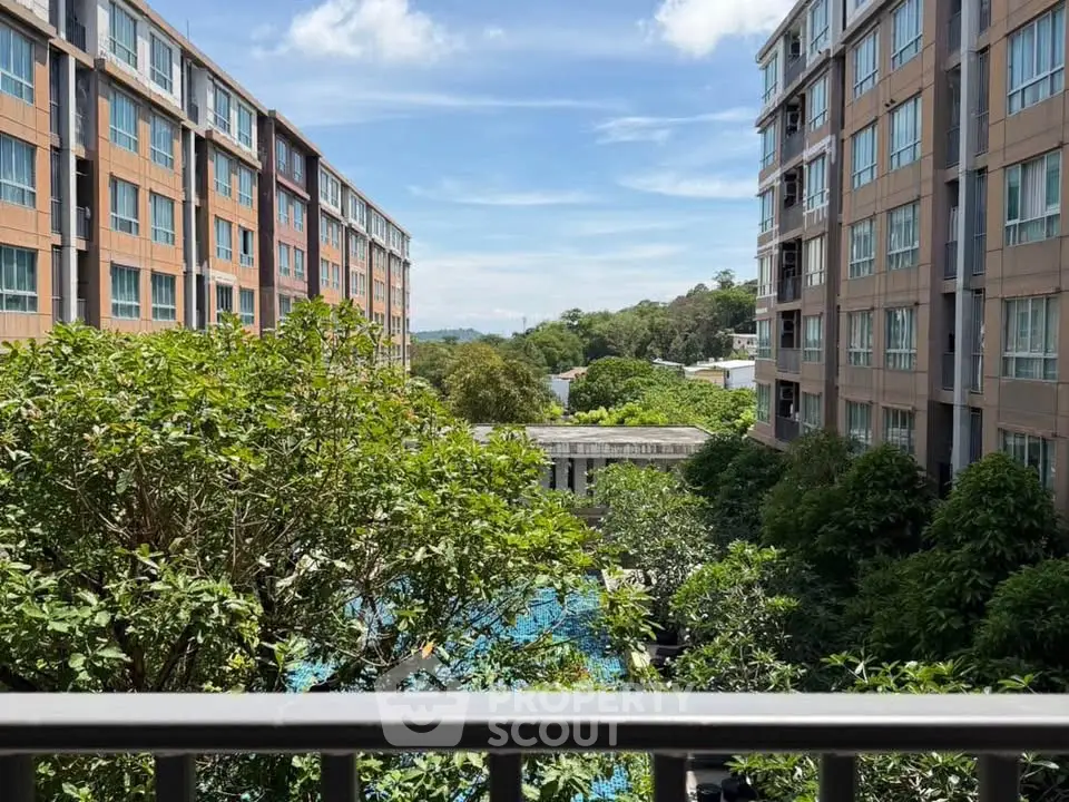 Scenic view from balcony overlooking lush garden and modern apartment buildings.