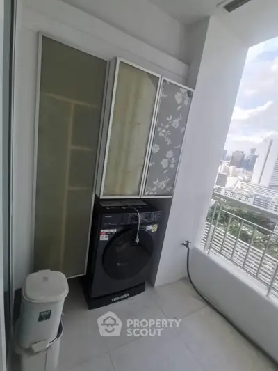 Compact balcony with washing machine and city view, ideal for urban living.