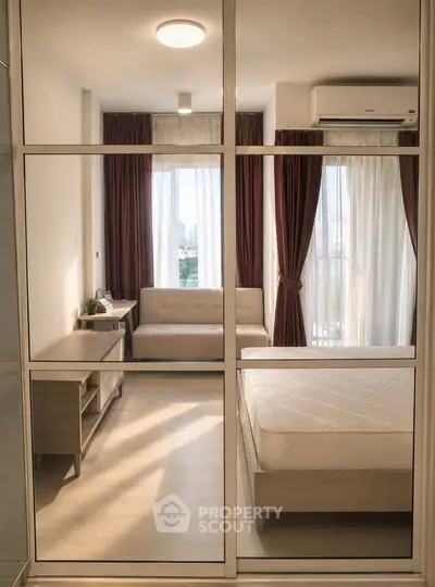 Modern bedroom with glass partition, cozy sofa, and natural light in a stylish apartment.