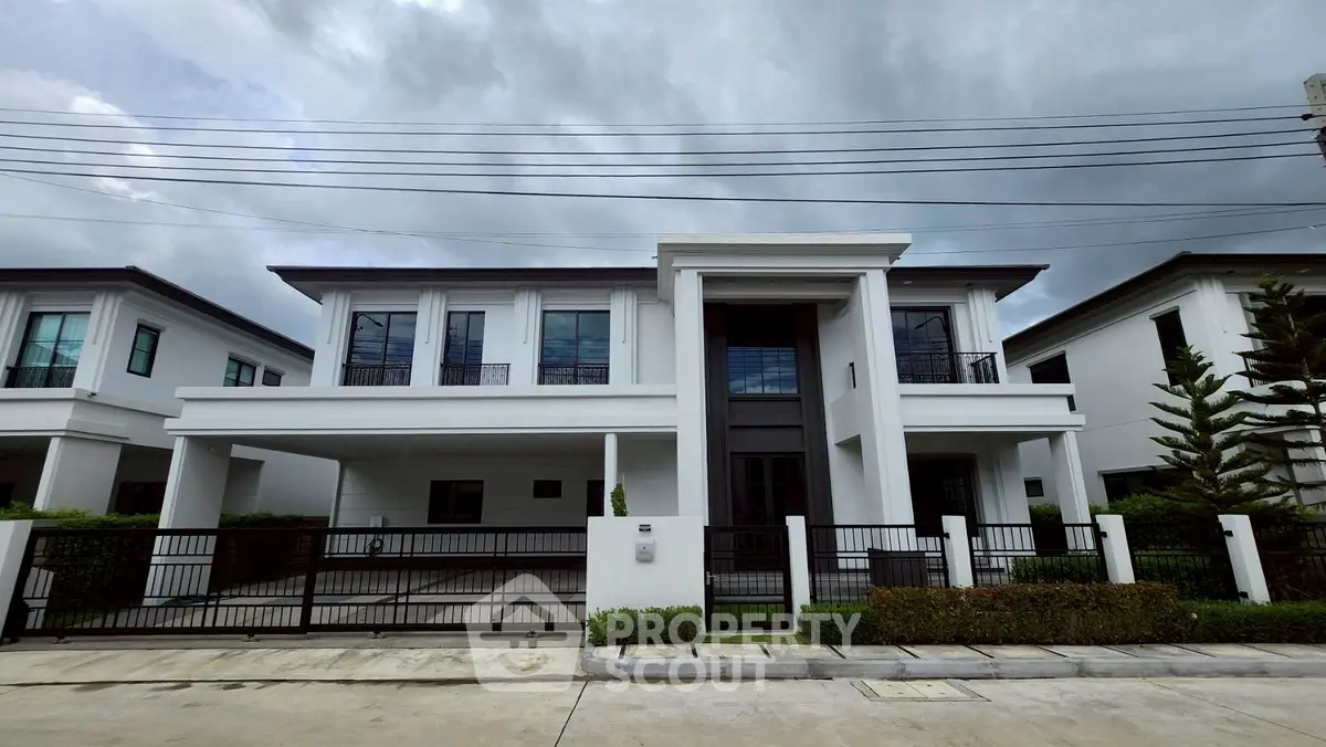 Modern two-story white house with gated driveway and lush greenery