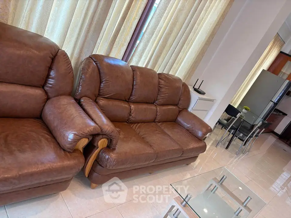 Spacious living room with leather sofas and glass coffee table