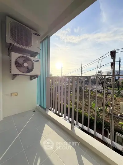 Spacious balcony with air conditioning units and scenic view of the city skyline at sunset.