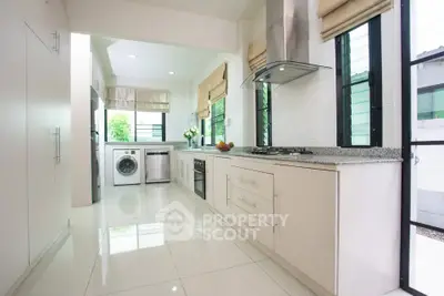 Modern kitchen with sleek appliances and open layout, featuring a washing machine and gas stove.