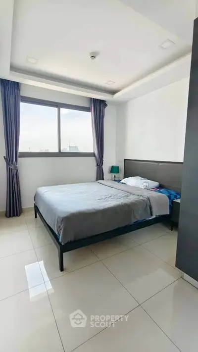 Modern bedroom with large window and sleek design in a bright apartment.