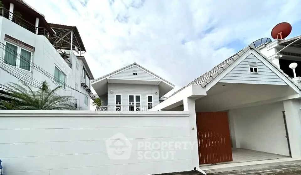 Charming white house with modern design and spacious carport in a serene neighborhood.