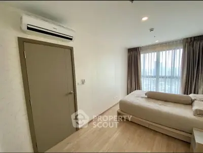 Spacious bedroom with large window and modern air conditioning unit, offering comfort and natural light.