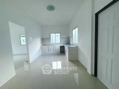 Spacious minimalist kitchen with sleek white tiles and ample natural light.