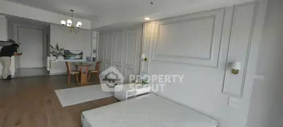 Spacious modern living room with elegant decor and dining area, featuring wooden flooring and stylish lighting.