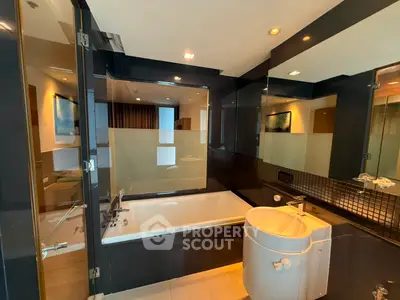 Luxurious modern bathroom with sleek black tiles and a spacious bathtub in a high-end apartment.