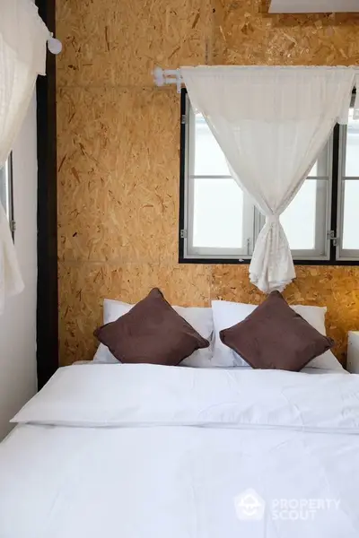 Cozy bedroom with rustic wooden wall and soft white bedding