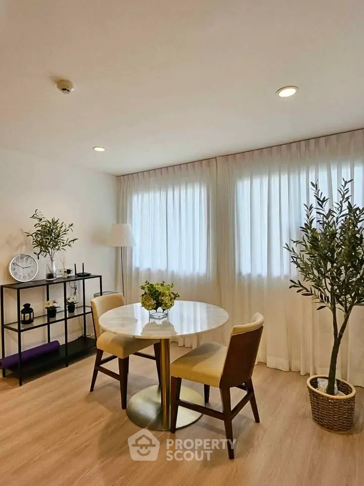 Charming dining area with elegant round table and chairs, complemented by natural light and tasteful decor.