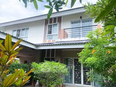 Charming two-story house with lush garden and modern balcony design.