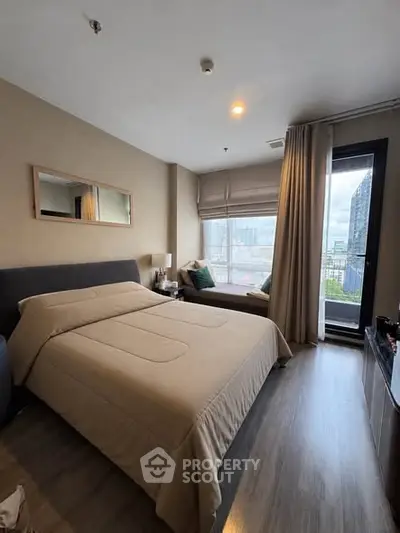 Modern bedroom with city view and cozy seating area by the window.