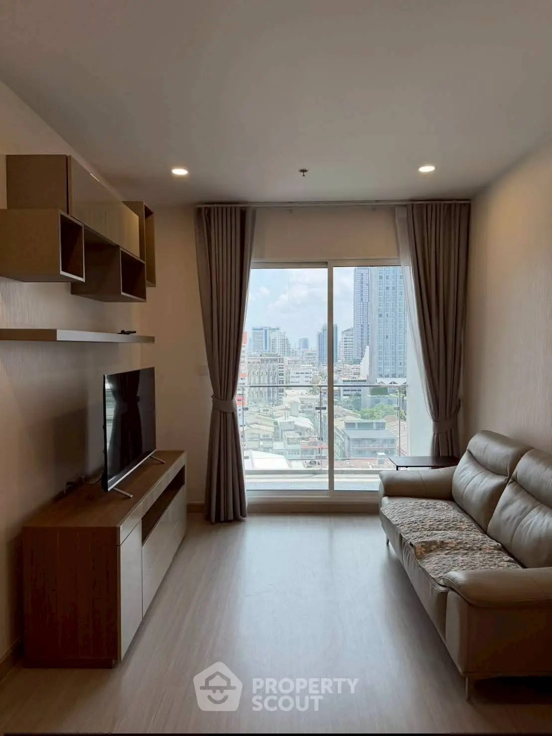 Modern living room with city view, featuring sleek furniture and large windows for natural light.