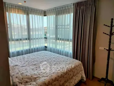 Cozy bedroom with large windows and elegant curtains in a modern apartment.