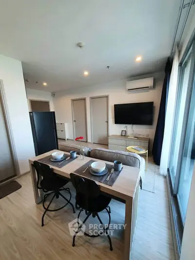 Modern open-plan living room with dining area and large windows in a stylish apartment.