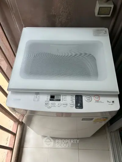 Modern washing machine on balcony with sleek design and digital controls.
