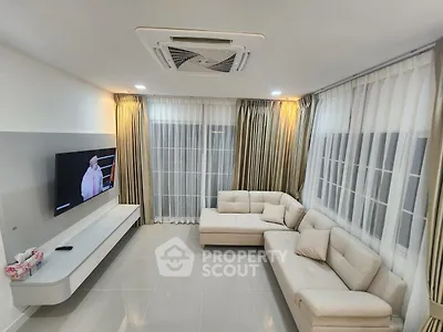 Modern living room with elegant sofa and large windows, perfect for relaxation and entertainment.