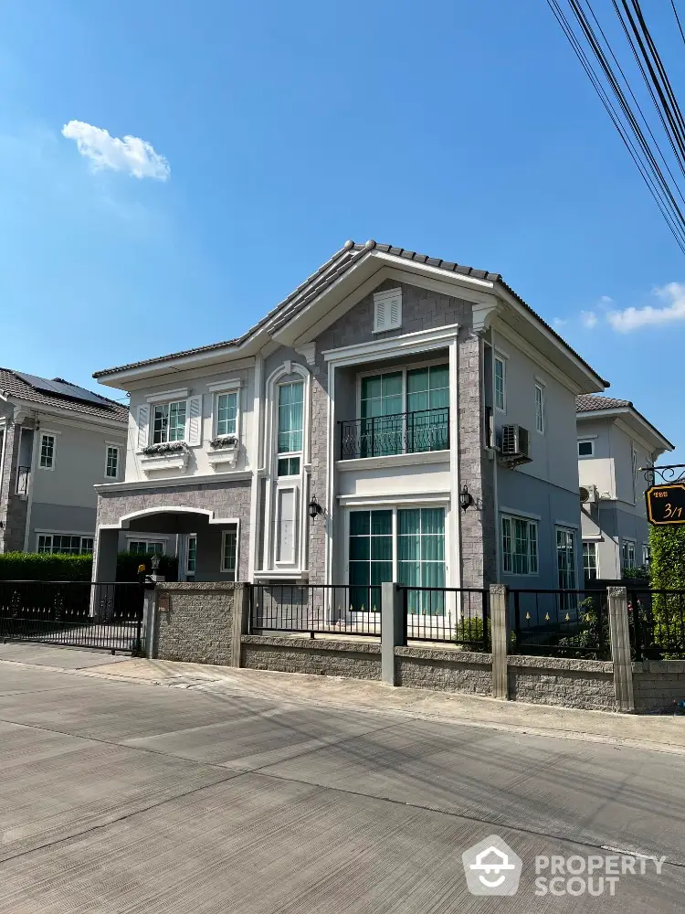 Elegant two-story house with modern facade and spacious driveway under clear blue sky.