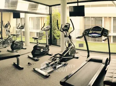 Modern gym with exercise equipment and large windows in luxury apartment building.